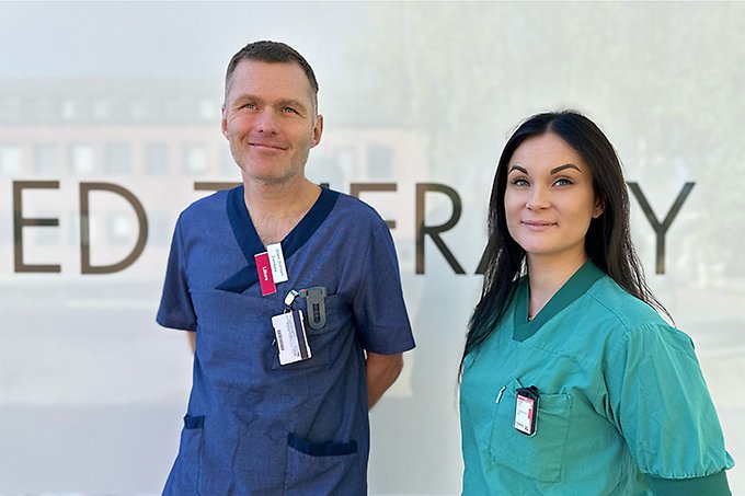 Två personer klädda i sjukhuskläder står intill varandra
