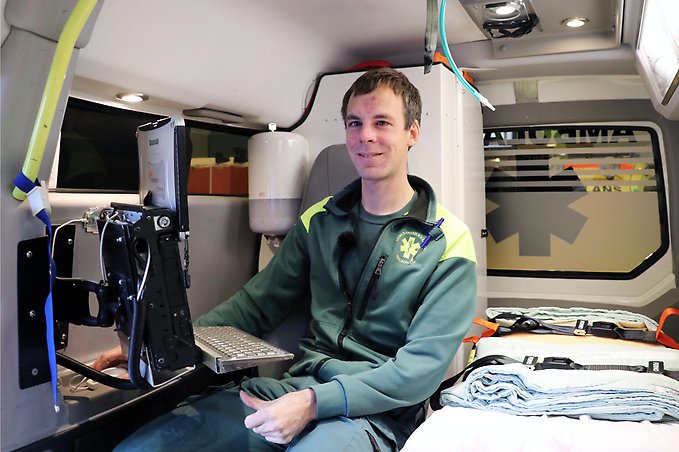en ambulanssjuksköterska sitter vid en dator inne i en ambulans
