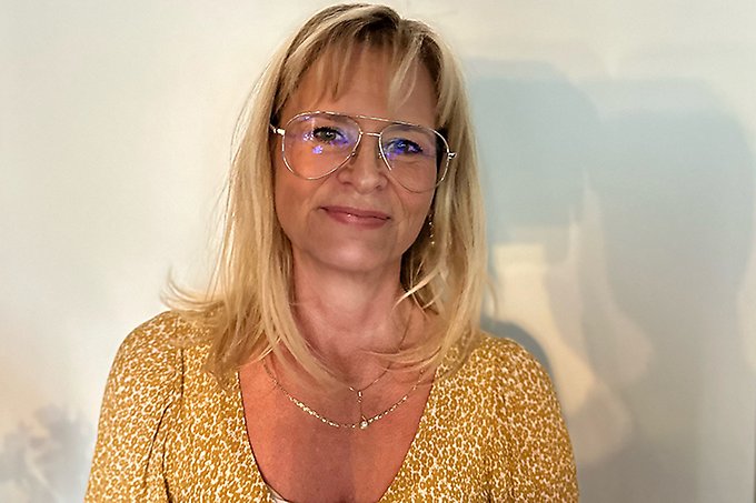 Person i ljust hår och glasögon och gul klänning