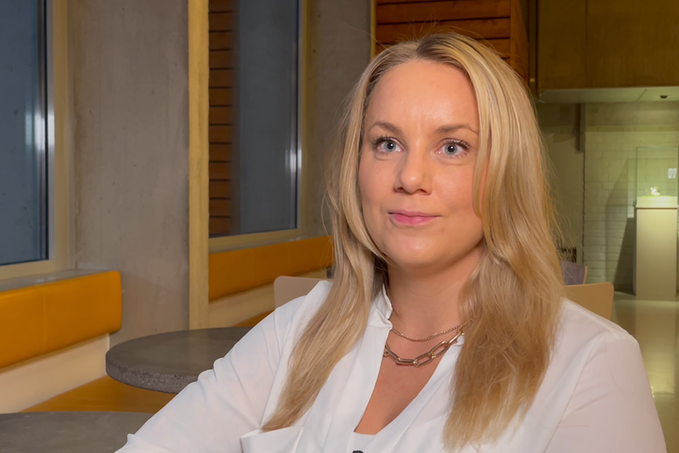 porträttbild på en person med långt ljust hår som sitter framför ett fönster