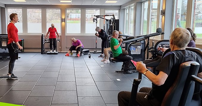 Personer som tränar i ett gym tillsammans med en ledare.