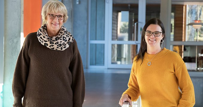 Två personer står på varsin sida om ett räcke.