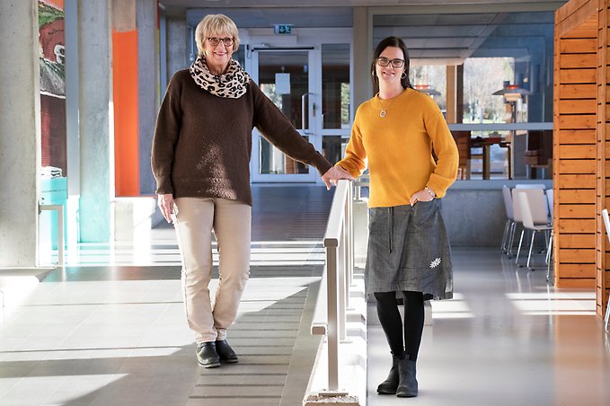 Två personer står på varsin sida om ett räcke.