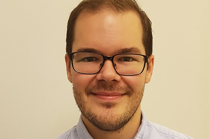 En person ler in i kameran iklädd skjorta