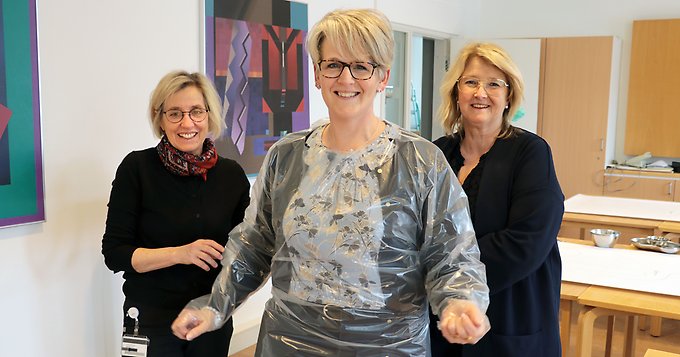 tre personer varav en är klädd i ett plastförkläde
